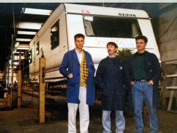 Kot vodja tehnologije v brežiški tovarni Adria Caravan je Ernest Sečen  (v sredini) 13. oktobra 1992 skupaj s kolegoma tehnologoma takole  pospremil zadnjo prikolico, narejeno v tej tovarni. Slika ni  najostrejša, so pa pomembne številke na njej. Z rdečo piše, katera po  vrsti je bila izdelana v Brežicah (54.670), in datum, ko je zadnja  prikolica zapustila tovarniško halo (13. 10. 1992 – nesrečni trinajsti  ...). V tovarniški hali je danes trgovski center Intermarket. Na tem  mestu, na katerem je nastala slika, je zdaj Merkur. (Foto: osebni arhiv  E. S.)