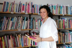 Zala Štamcar med knjigami v zdajšnji knjižnici v Metelkovini. Za delo v novih prostorih ima že kup idej. (Foto: L. M.)